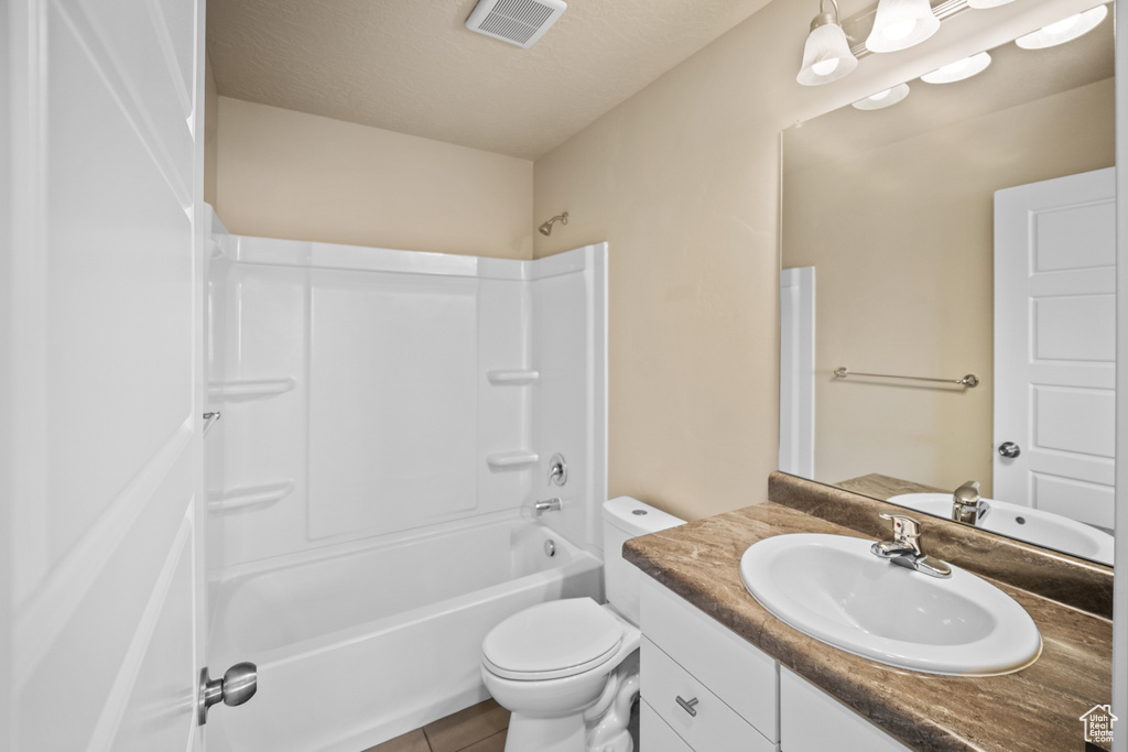 Full bathroom featuring large vanity, a textured ceiling, shower / bath combination, tile floors, and toilet