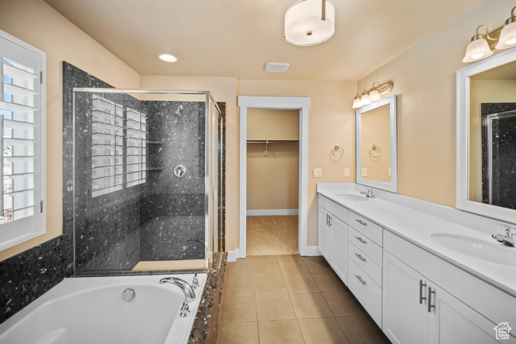 Bathroom featuring vanity with extensive cabinet space, double sink, tile floors, and independent shower and bath