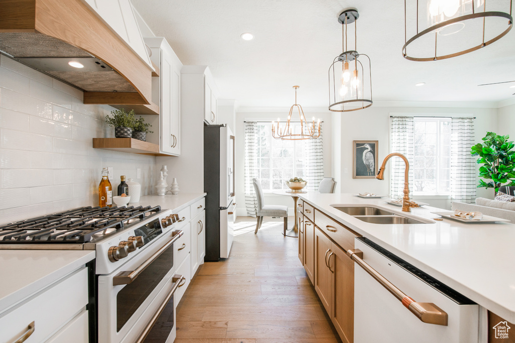 Kitchen featuring white cabinets, sink, white appliances, backsplash, and light hardwood / wood-style flooring