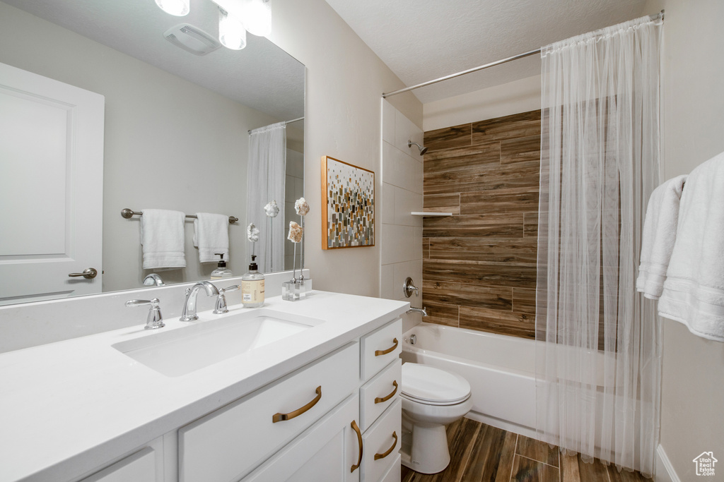 Full bathroom with vanity with extensive cabinet space, toilet, and shower / bath combo with shower curtain