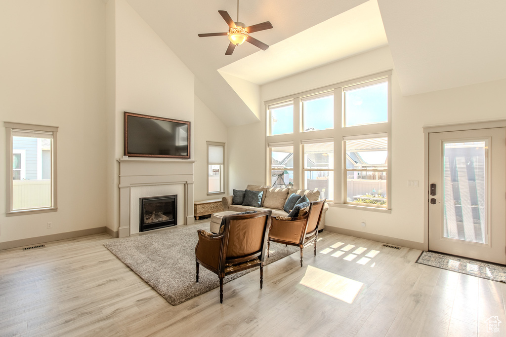 Living room featuring high vaulted ceiling, light hardwood / wood-style floors, and ceiling fan
