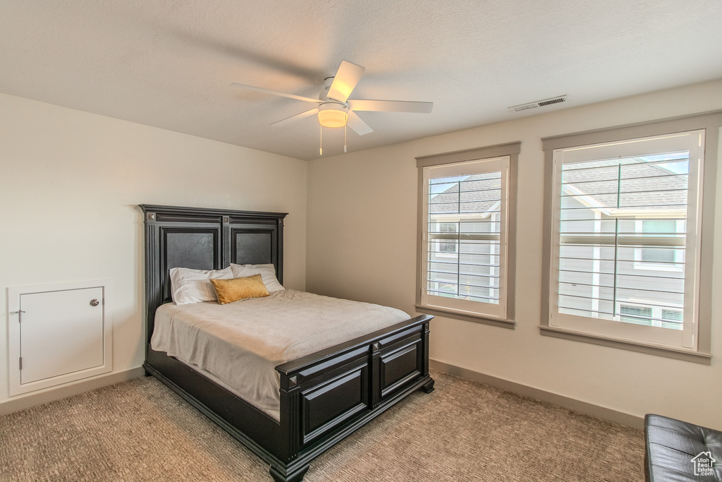 Bedroom with light carpet, multiple windows, and ceiling fan