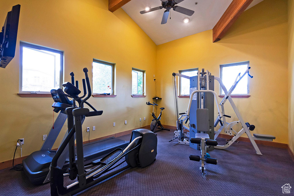 Exercise room with dark colored carpet, ceiling fan, and vaulted ceiling
