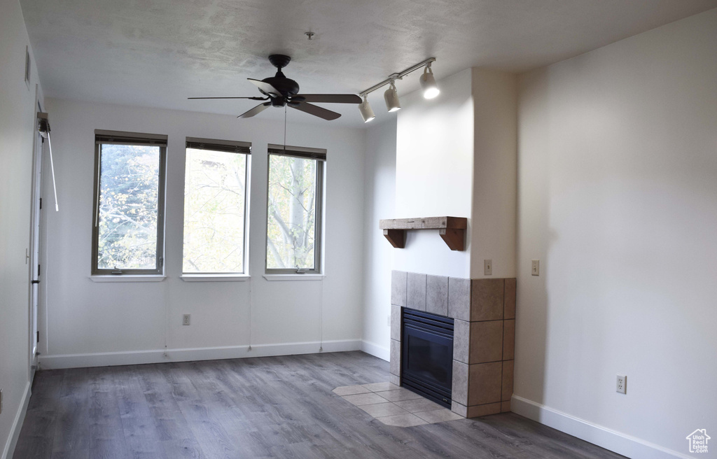 Unfurnished living room with ceiling fan, a tile fireplace, hardwood / wood-style flooring, and track lighting