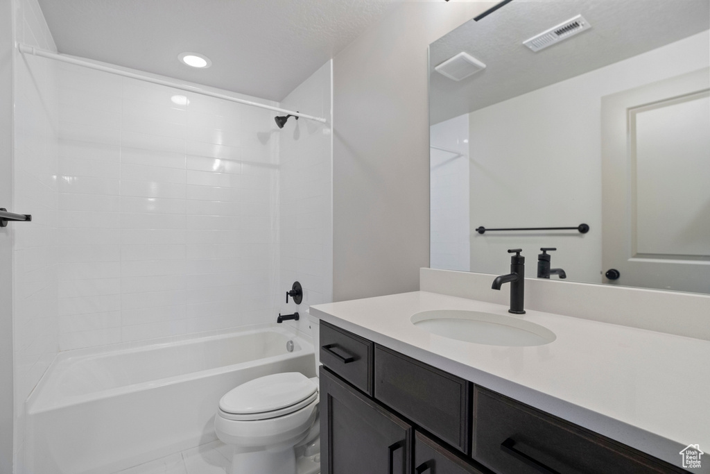 Full bathroom featuring tiled shower / bath combo, oversized vanity, toilet, and tile floors