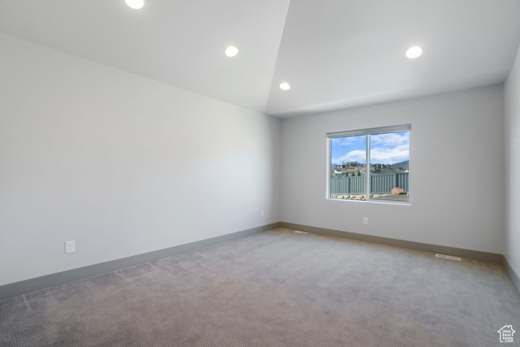 Unfurnished room with light colored carpet and vaulted ceiling