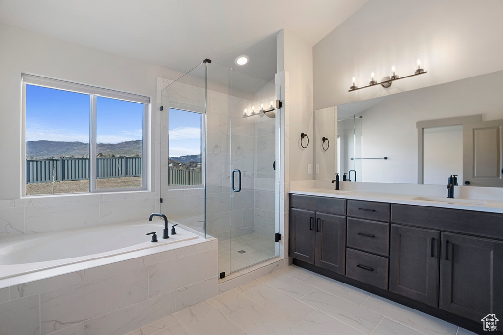Bathroom featuring dual sinks, vanity with extensive cabinet space, independent shower and bath, a mountain view, and tile flooring