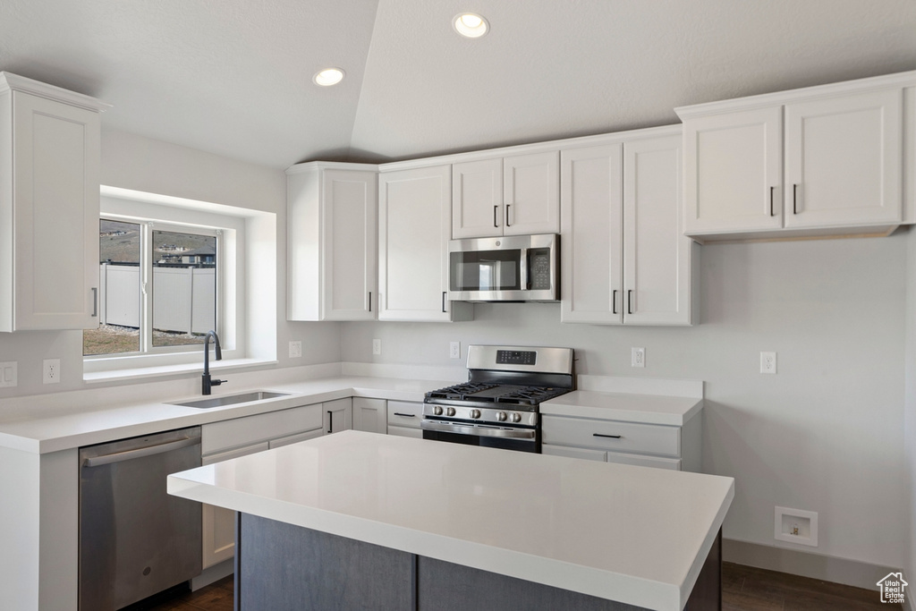 Kitchen with white cabinets, a kitchen island, dark hardwood / wood-style floors, stainless steel appliances, and sink
