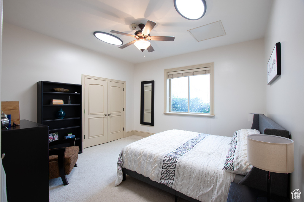 Bedroom with ceiling fan, light carpet, and a closet