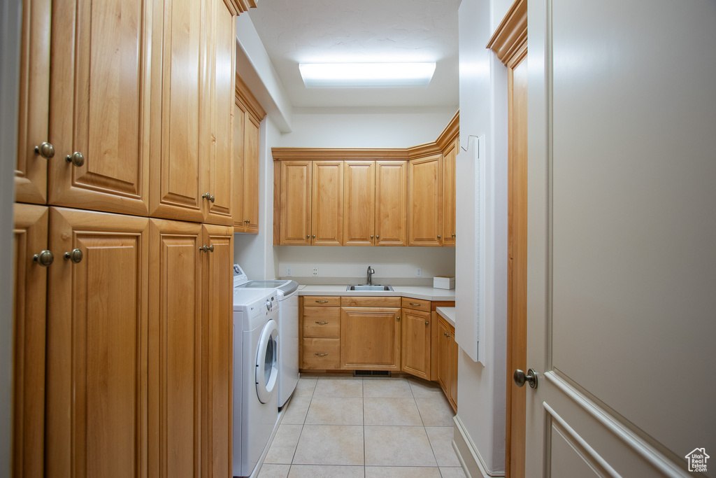 Laundry area with sink, light tile floors, cabinets, and washer and clothes dryer