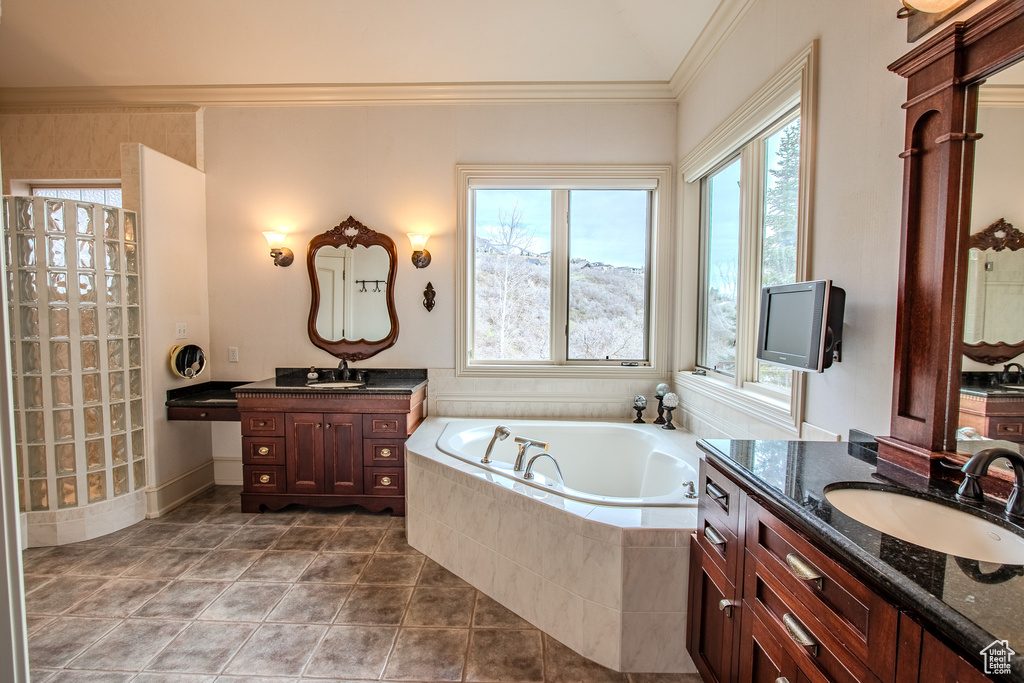 Bathroom featuring ornamental molding, a relaxing tiled bath, tile flooring, and dual bowl vanity