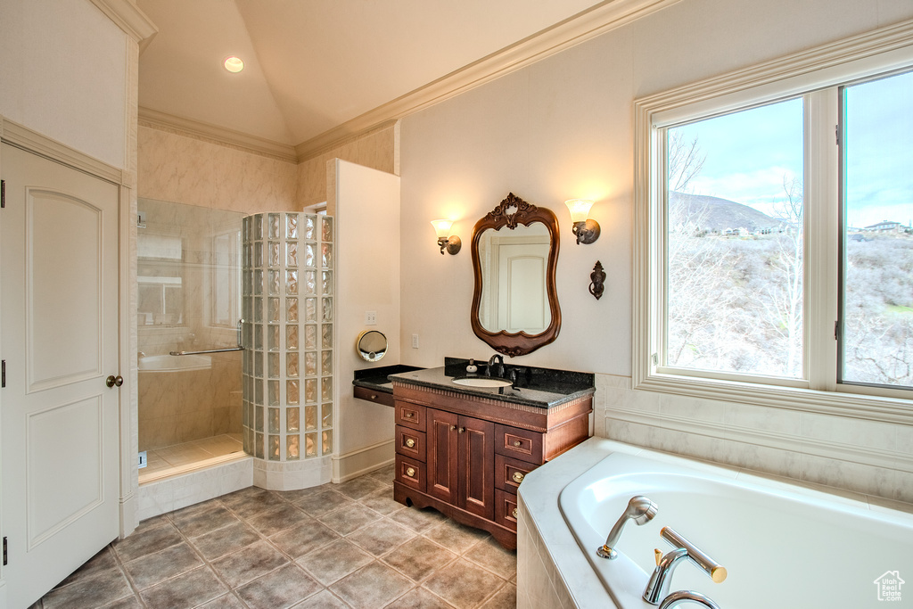 Bathroom featuring tile floors, shower with separate bathtub, vaulted ceiling, large vanity, and ornamental molding