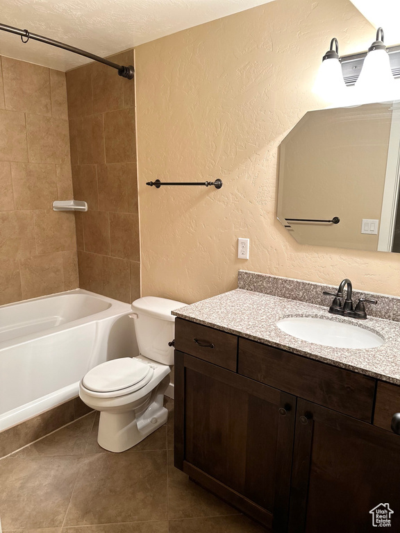 Full bathroom featuring toilet, tiled shower / bath, tile flooring, a textured ceiling, and vanity