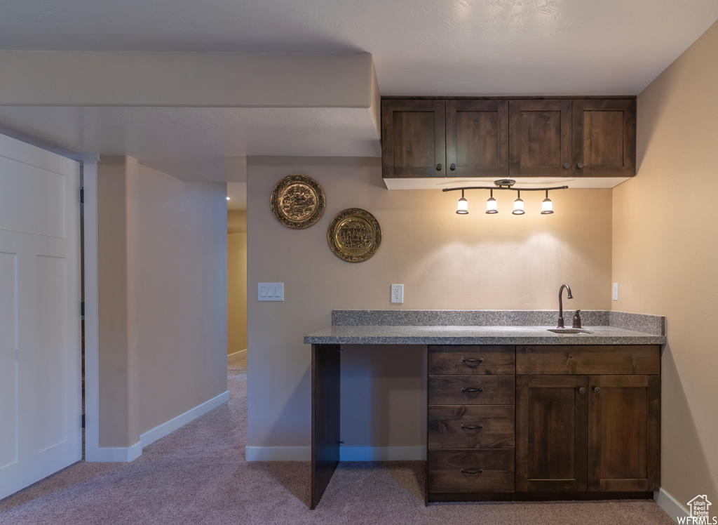 Bar featuring dark brown cabinets, light carpet, and sink
