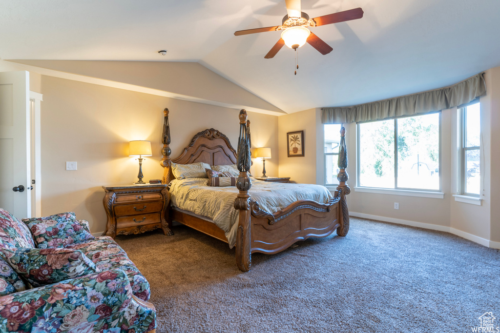 Bedroom with dark carpet, ceiling fan, and vaulted ceiling