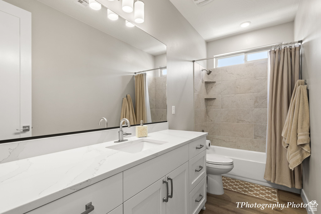 Full bathroom featuring shower / bath combo, vanity, toilet, and hardwood / wood-style flooring