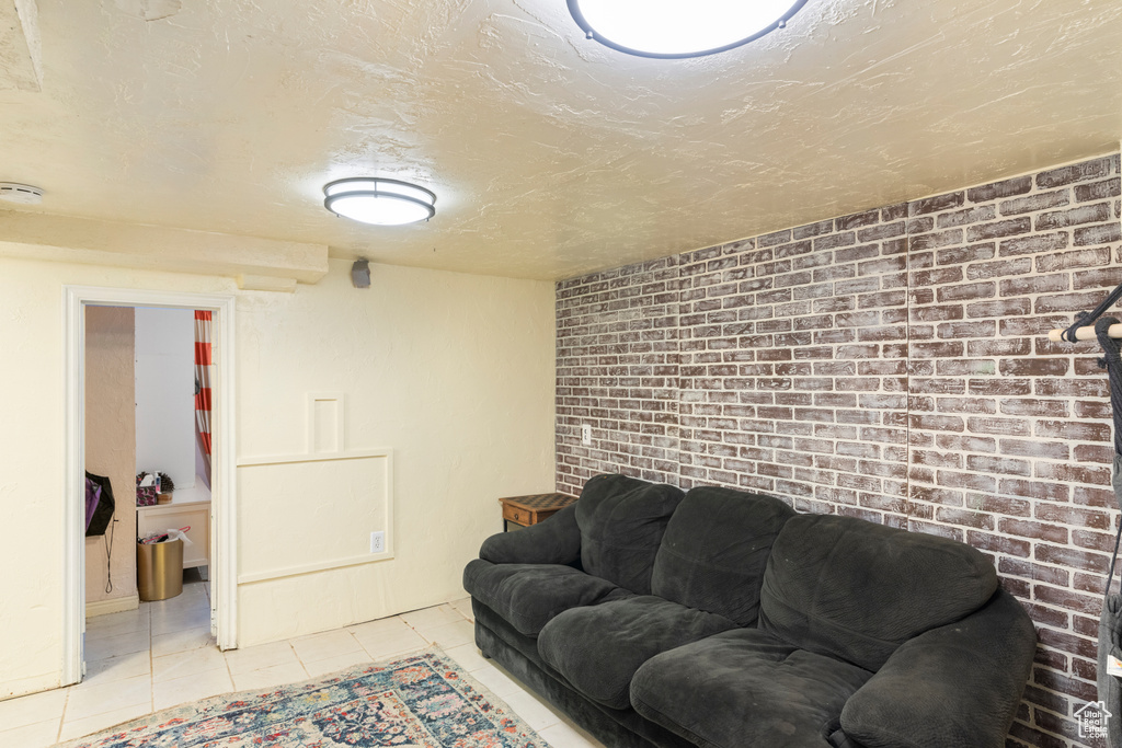 Tiled living room featuring a textured ceiling and brick wall