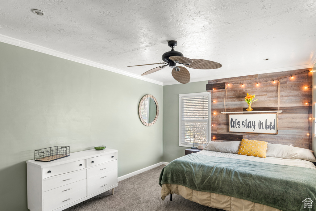 Bedroom with ceiling fan, dark carpet, a textured ceiling, and ornamental molding