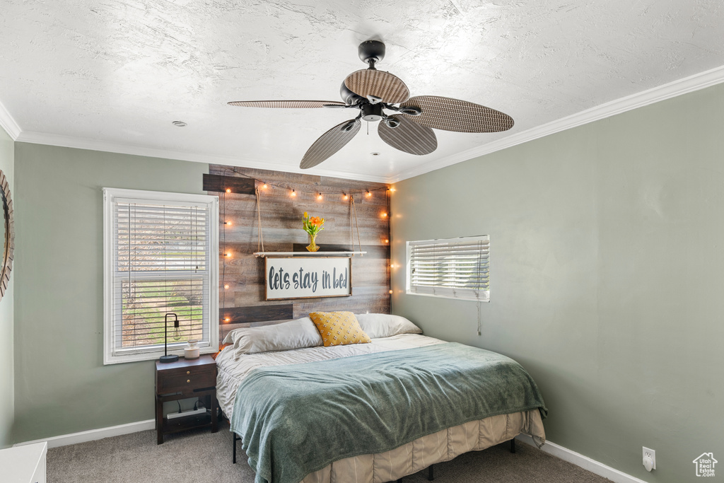 Bedroom featuring ornamental molding, ceiling fan, carpet, and wood walls