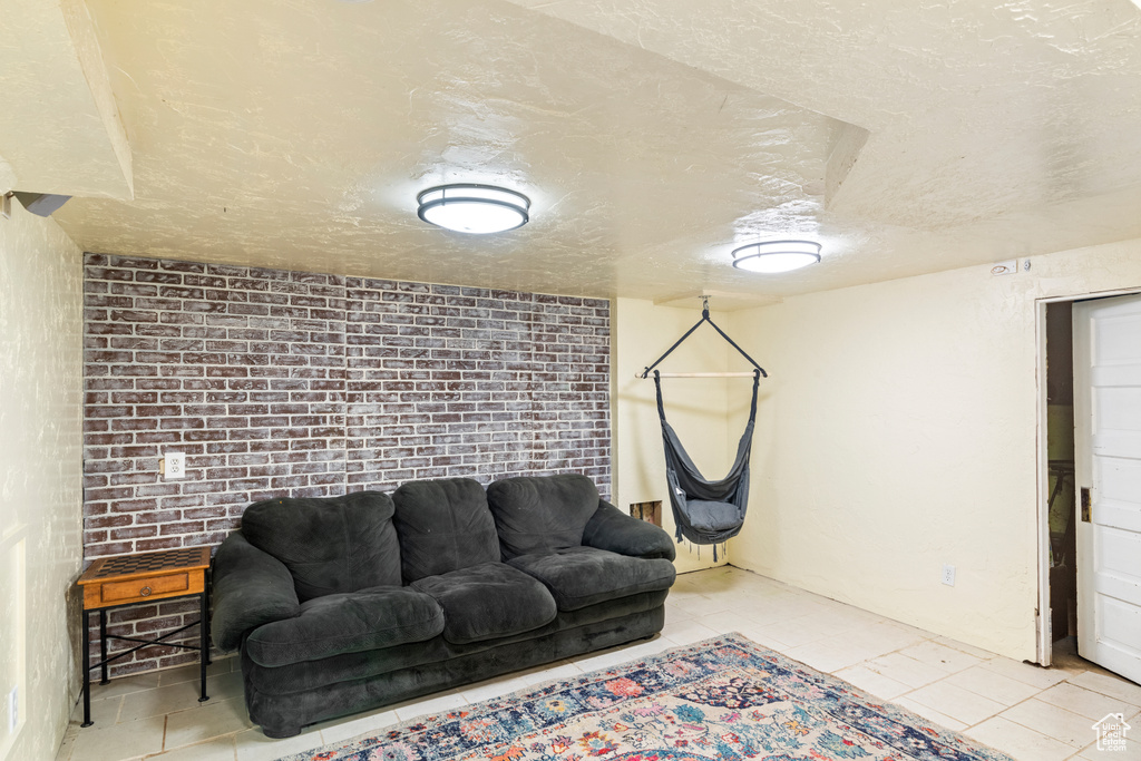 Living room featuring a textured ceiling, brick wall, and light tile floors