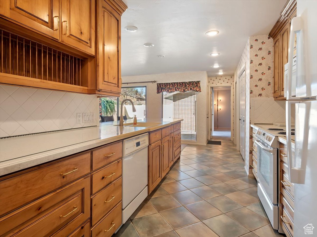 Kitchen with backsplash, white appliances, sink, and dark tile floors