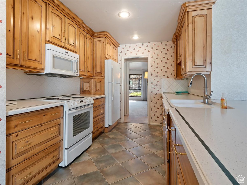 Kitchen featuring white appliances, dark colored carpet, sink, and tasteful backsplash