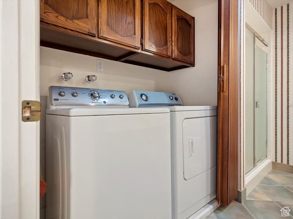 Laundry room featuring cabinets, light tile floors, and washer and clothes dryer