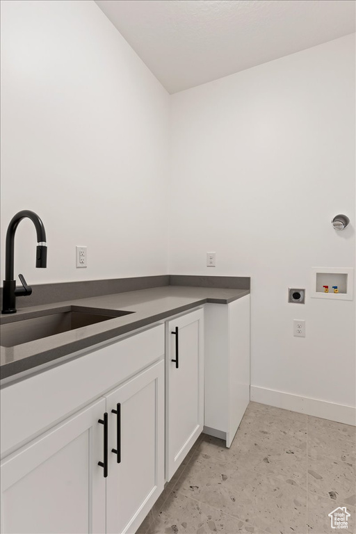 Clothes washing area featuring hookup for an electric dryer, sink, light tile flooring, and cabinets