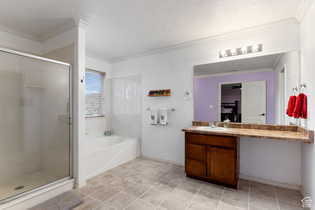 Bathroom featuring a textured ceiling, ornamental molding, vanity, and separate shower and tub