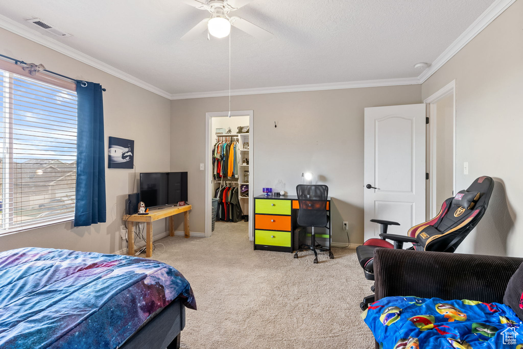 Bedroom with light colored carpet, a closet, ornamental molding, and a spacious closet