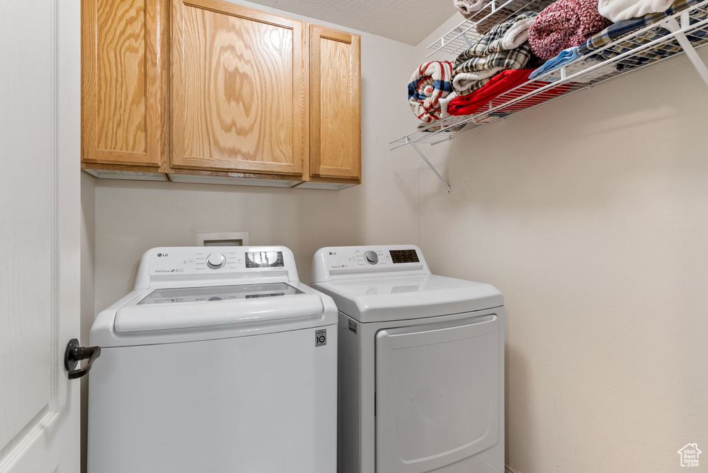 Clothes washing area featuring cabinets and separate washer and dryer