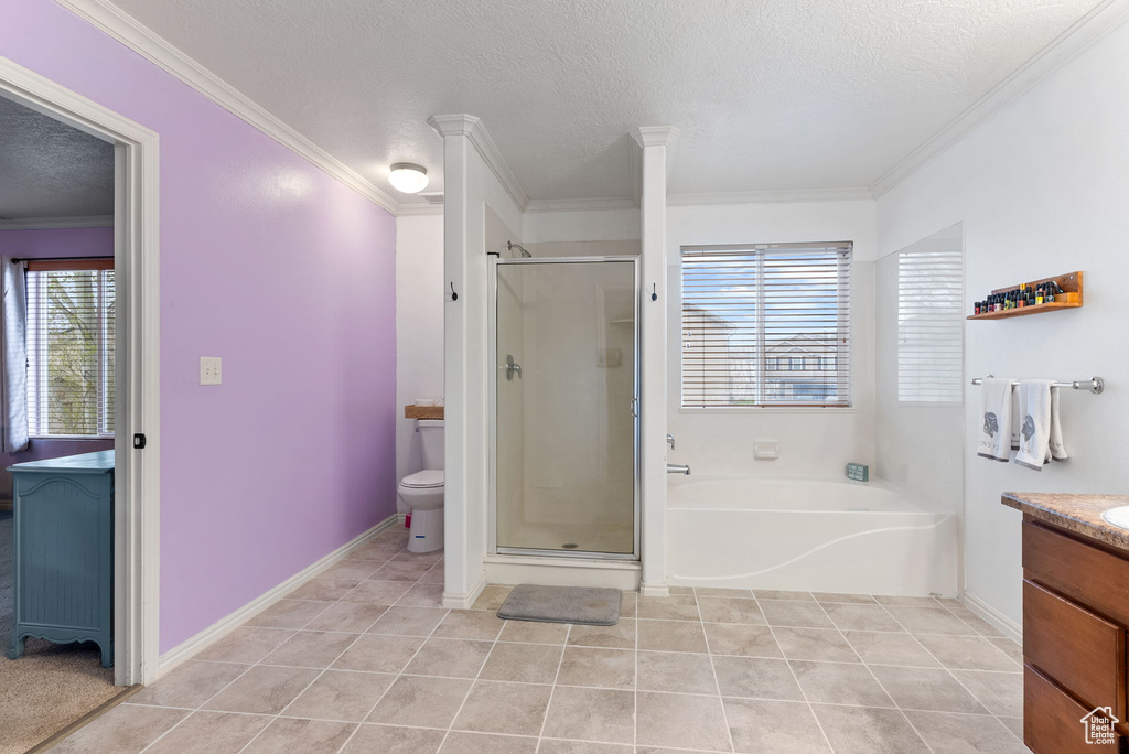 Full bathroom with crown molding, tile floors, vanity, shower with separate bathtub, and toilet