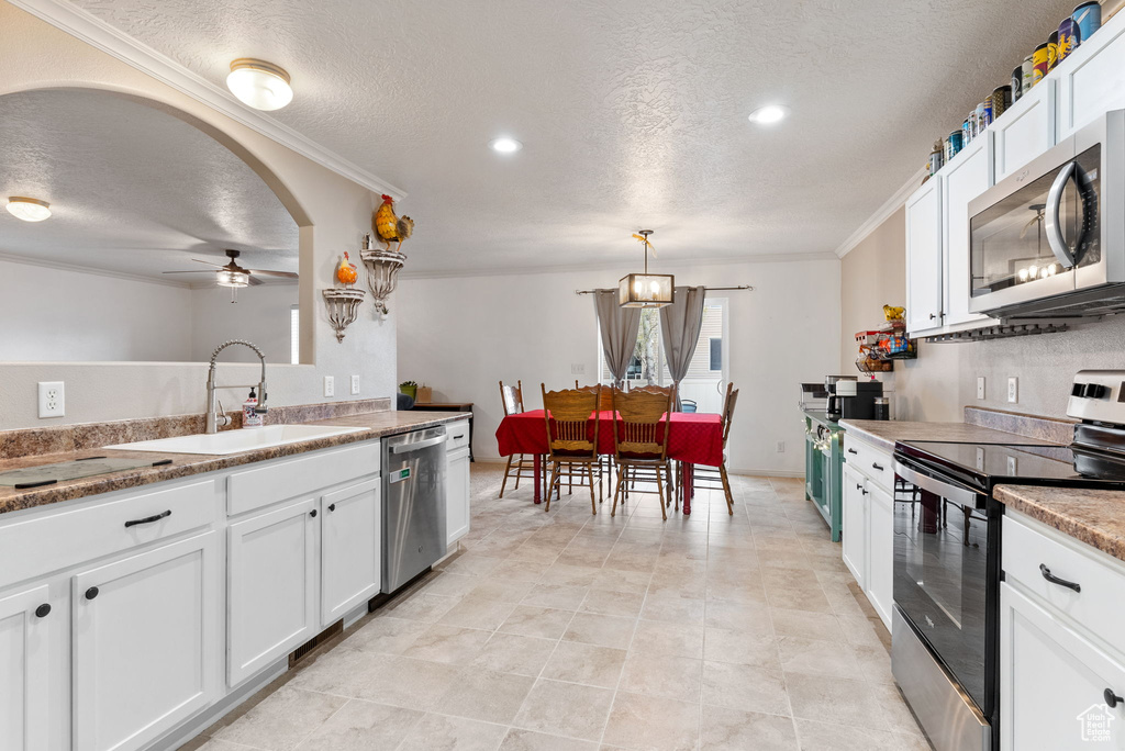 Kitchen featuring crown molding, appliances with stainless steel finishes, and white cabinets