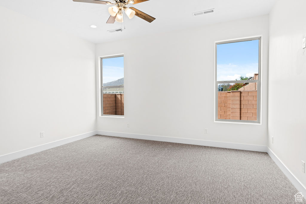 Empty room featuring ceiling fan and light carpet