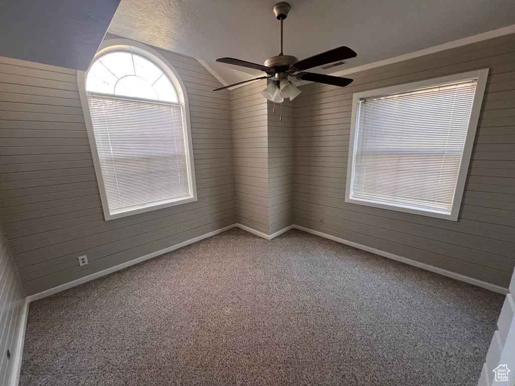 Empty room with ceiling fan, light carpet, and vaulted ceiling