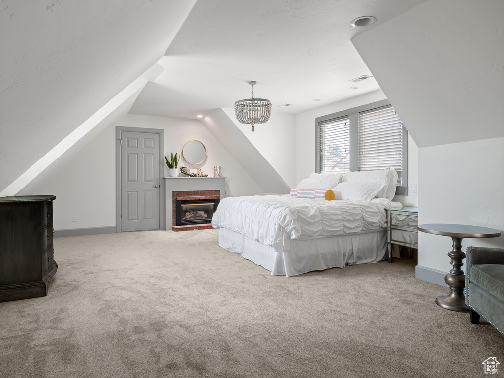 Bedroom featuring light colored carpet, lofted ceiling, a chandelier, and a brick fireplace