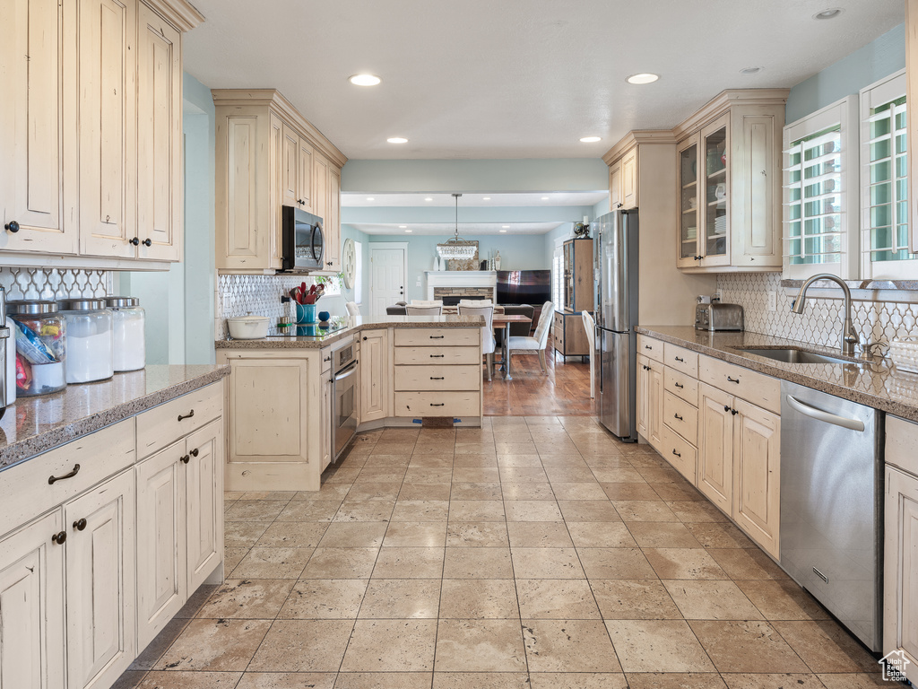 Kitchen featuring tasteful backsplash, stainless steel appliances, sink, and light tile floors