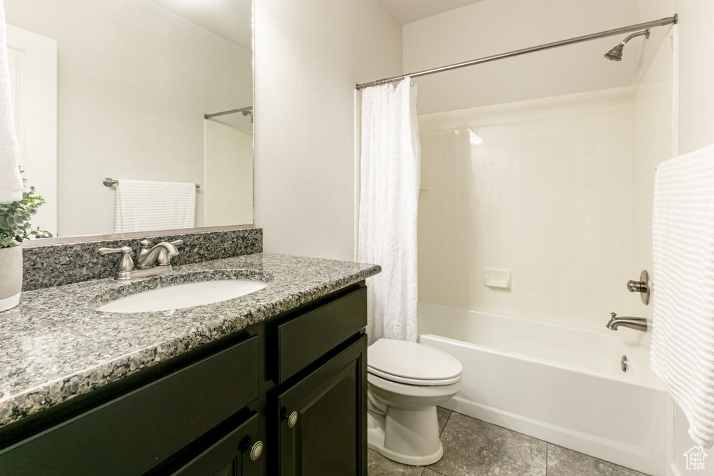 Full bathroom featuring vanity with extensive cabinet space, toilet, tile flooring, and shower / bath combo with shower curtain