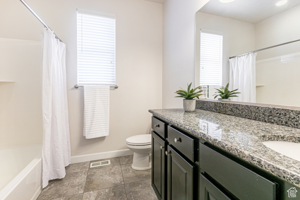 Full bathroom with plenty of natural light, vanity, shower / bath combination with curtain, and toilet