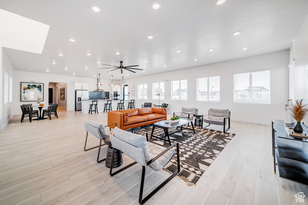 Living room featuring a skylight, light hardwood / wood-style flooring, and ceiling fan