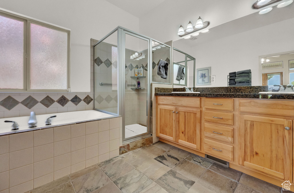 Bathroom featuring double vanity, tile floors, and plus walk in shower