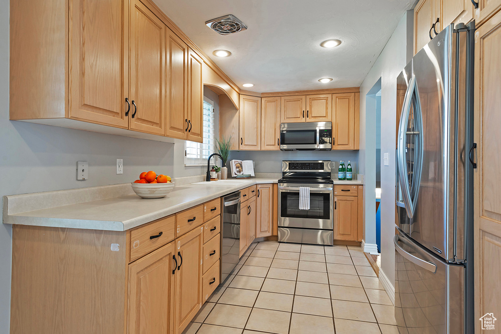 Kitchen featuring light brown cabinets, sink, stainless steel appliances, and light tile floors