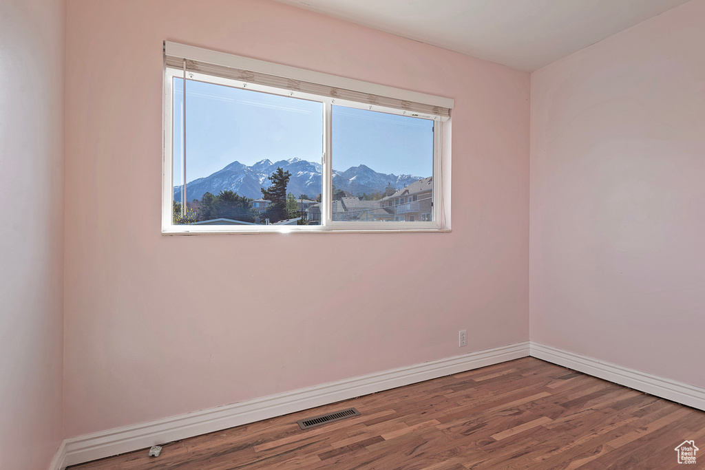 Empty room with a mountain view and dark wood-type flooring