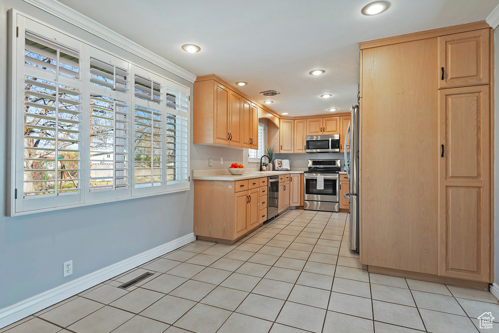 Kitchen featuring appliances with stainless steel finishes, light brown cabinets, and light tile floors