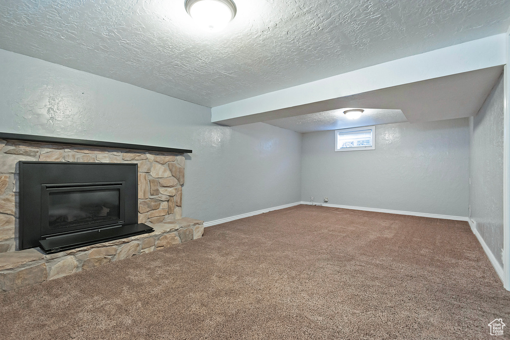 Basement featuring a fireplace, carpet, and a textured ceiling