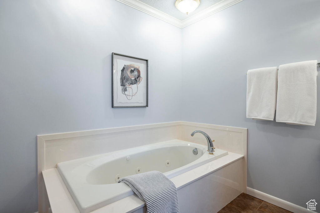 Bathroom with a bathing tub, crown molding, and tile floors