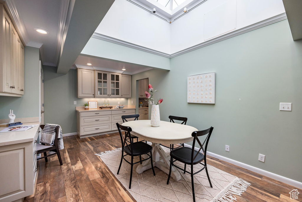 Dining space featuring a skylight, dark wood-type flooring, and ornamental molding