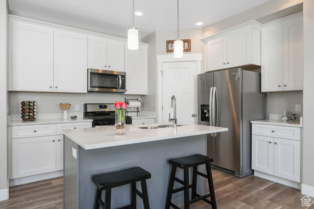 Kitchen with appliances with stainless steel finishes, dark hardwood / wood-style flooring, white cabinetry, and sink