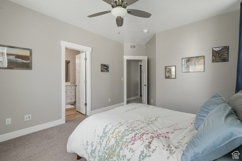 Bedroom with ceiling fan, connected bathroom, and light colored carpet