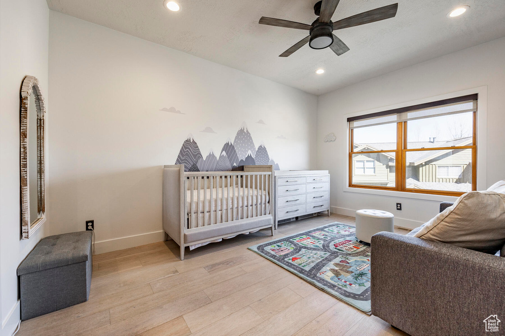 Bedroom featuring ceiling fan, light wood-type flooring, and a nursery area